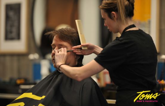 a man getting his hair trimmed by a barber